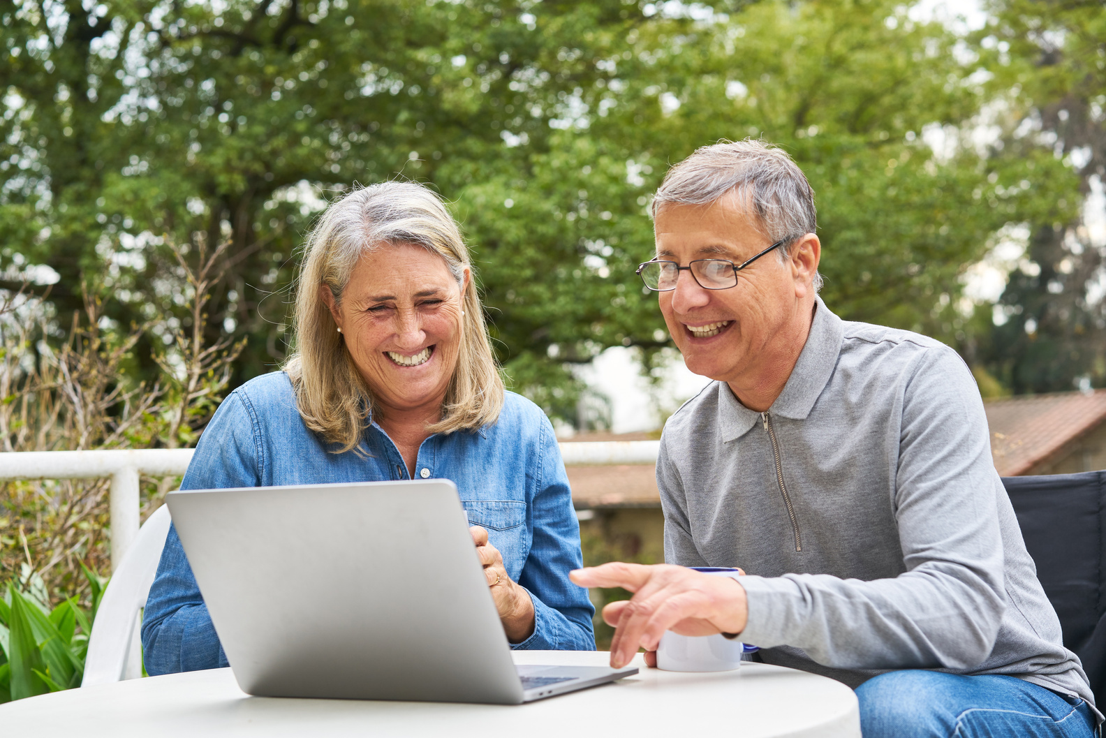 Happy Senior Couple Discussing over Laptop in Garden