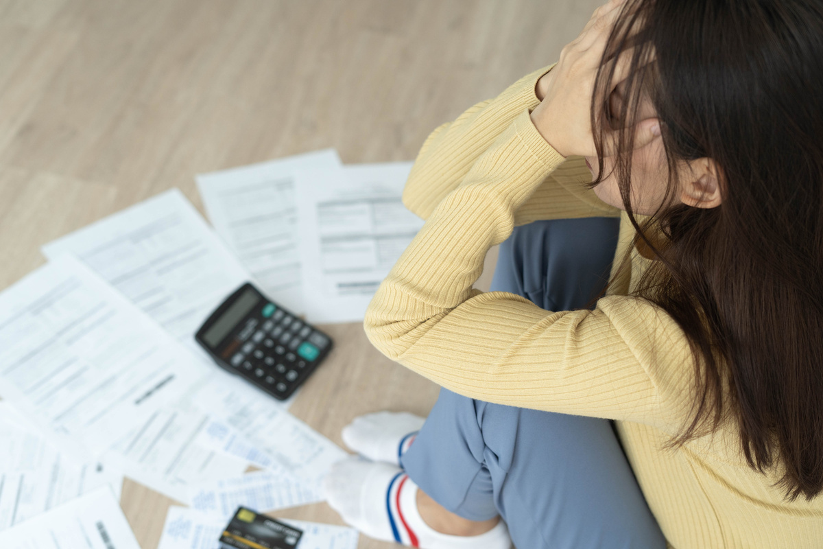 Woman Stressed with Bills Documents Papers on the Floor